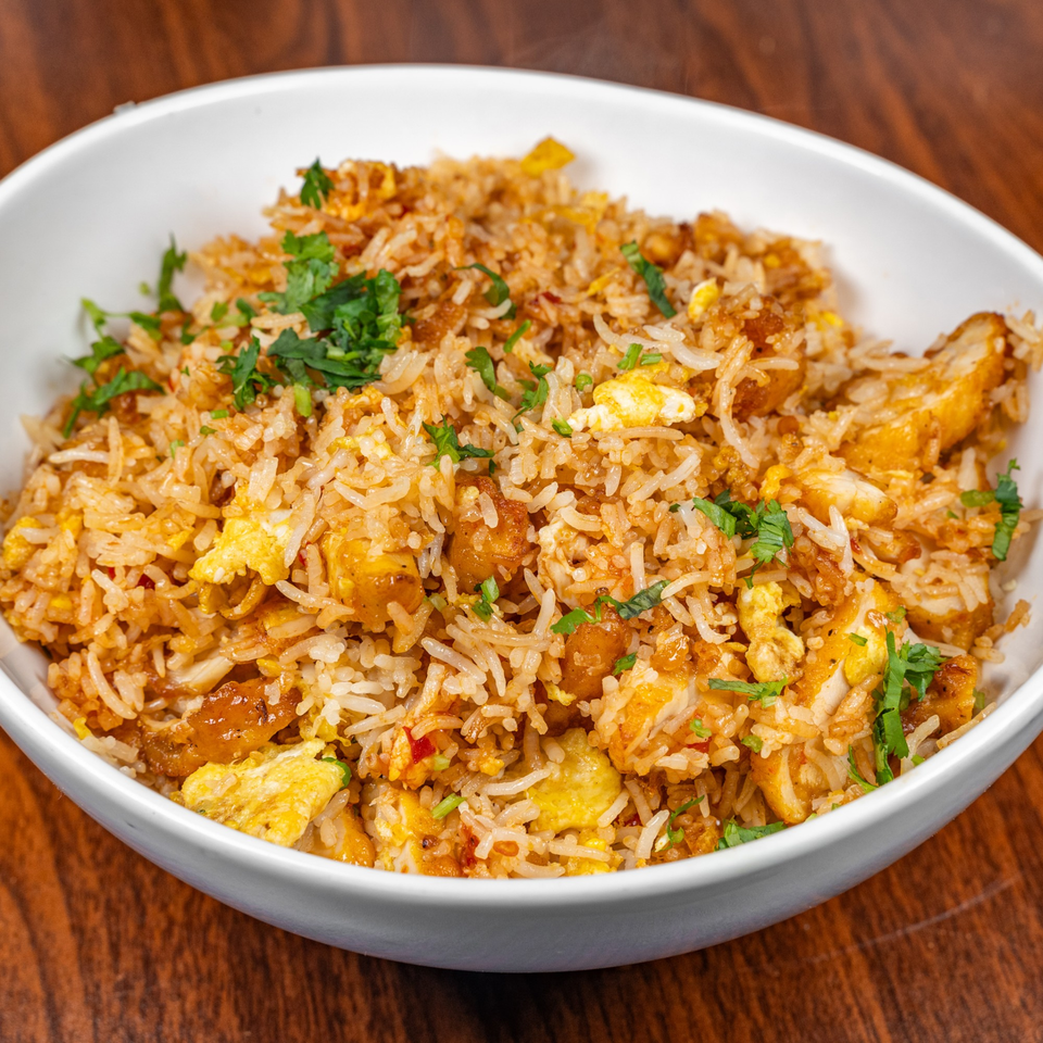 A white bowl filled with Suma's Kitchen halal fried rice, chicken, egg, and cilantro.