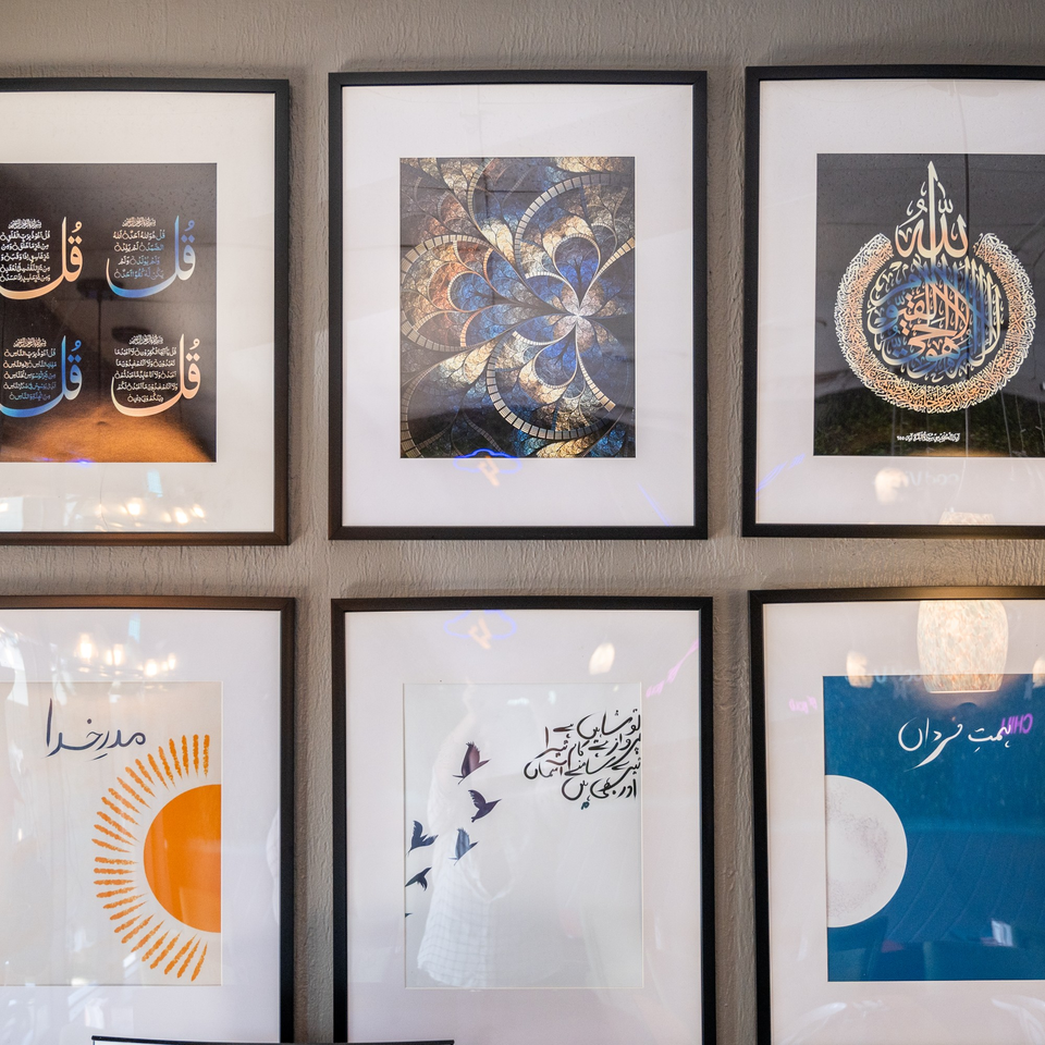 A gallery wall features six framed artworks, including Islamic calligraphy, abstract designs, and a sun graphic.