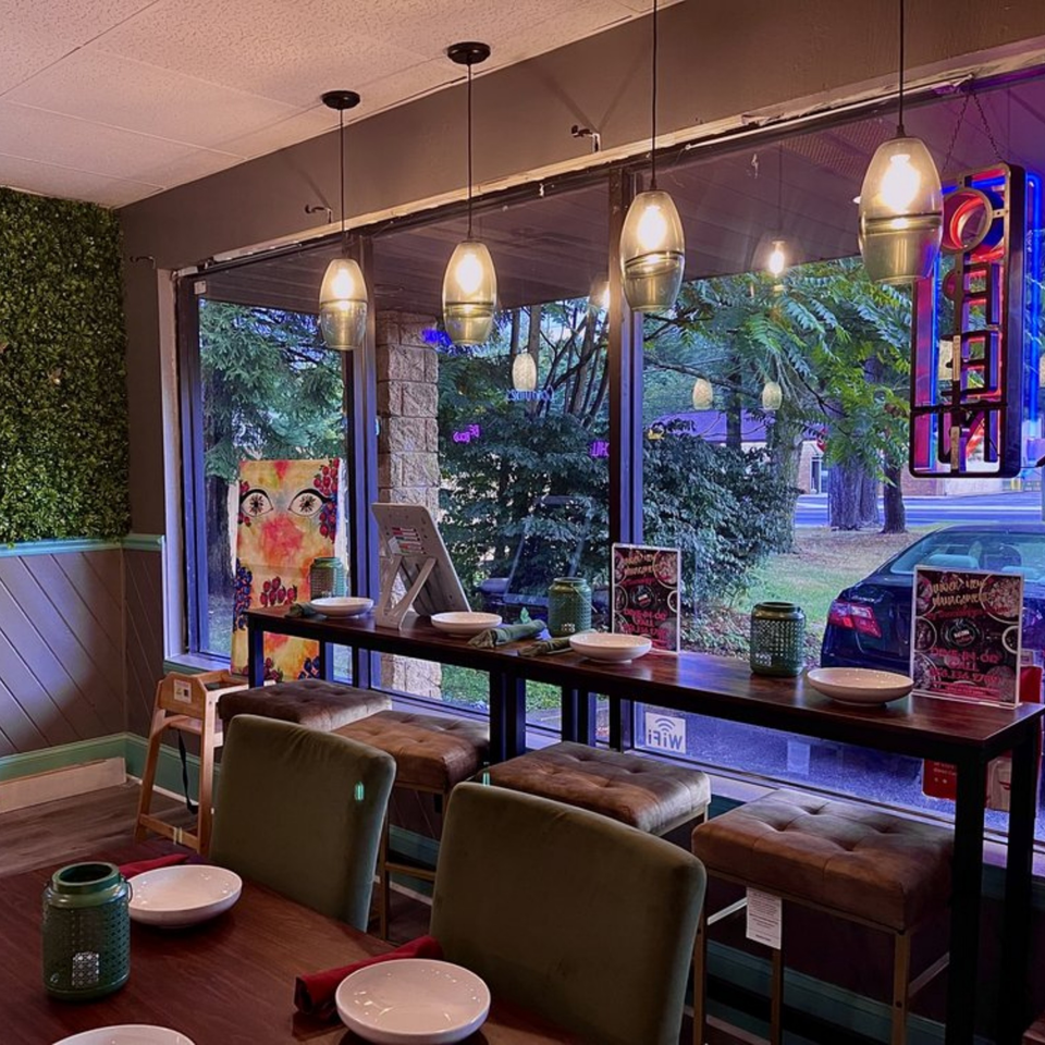 Interior of Suma's Kitchen with window seating, pendant lights, and a green accent wall.