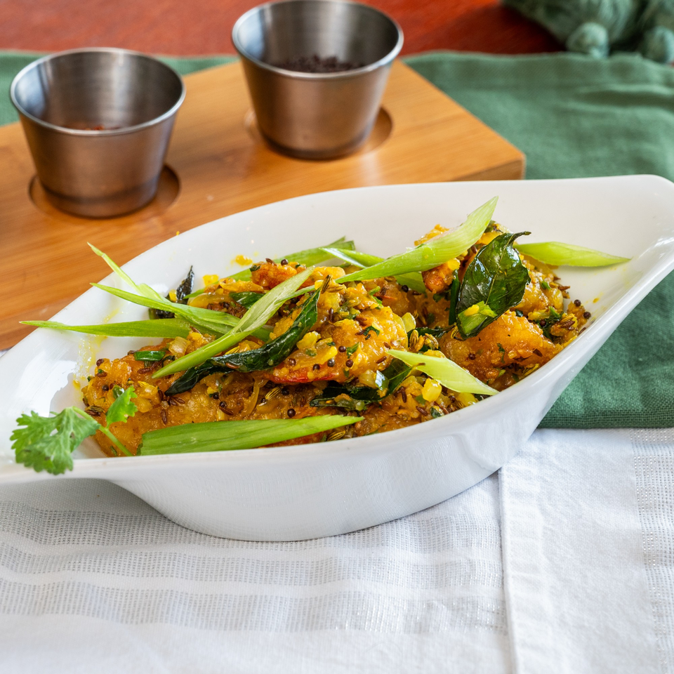 A white dish of Suma's Kitchen halal food, garnished with green onions and cilantro.