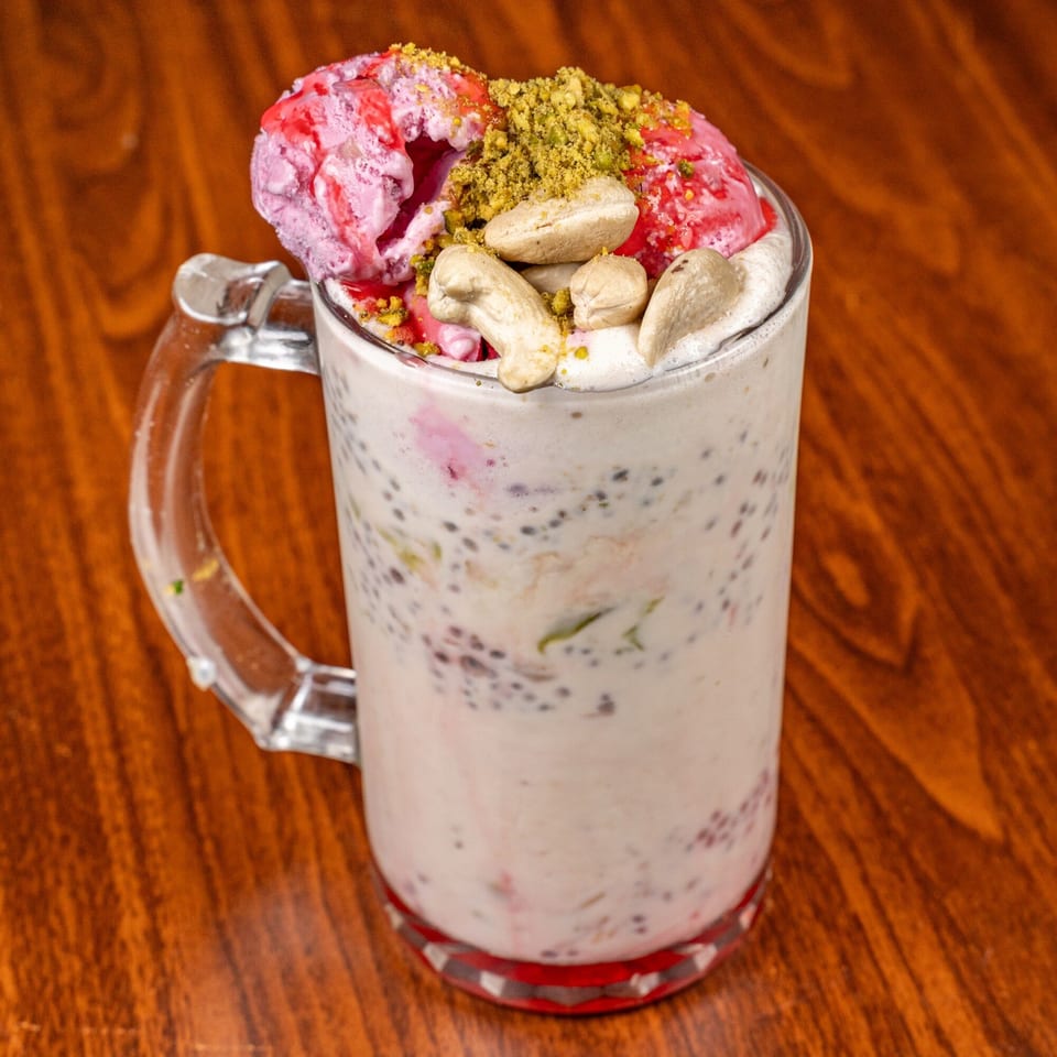 Suma's Kitchen Falooda with pink ice cream, cashews, and pistachios in a glass mug.
